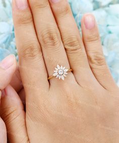 a woman's hand holding an engagement ring with a flower design on the band