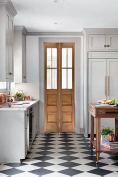 a black and white checkered floor in a kitchen with an open door to another room