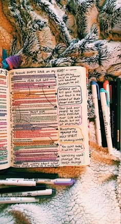 an open book with writing on it next to some pens and other items in the background