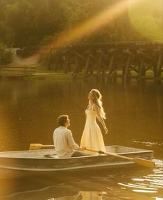 a man and woman in a row boat on the water with sunbeams behind them