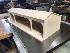 a wooden structure sitting on top of a metal table in a room filled with tools