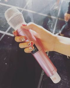 a woman holding a pink microphone in her hand with gold nail designs on the thumbnails