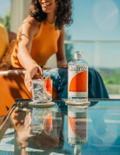 a woman sitting at a table with a bottle of water and ice cubes in front of her