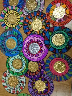 colorful paper plates with gold coins in them on a wooden surface, one has been made to look like an abstract painting