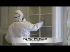 a person in white protective clothing spraying paint on a window with the words top coat oil based