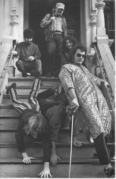 black and white photograph of people on steps with one person falling off the stairs, while another man is holding his cane