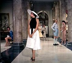 a woman in a white dress and hat walks down the runway at a fashion show