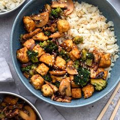 a bowl filled with rice, broccoli and tofu next to chopsticks