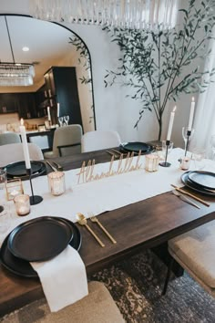 a dining room table is set with black plates and place settings for the guests to eat