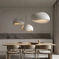 a dining room table with four lights hanging from the ceiling and chairs in front of it