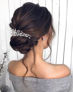 a woman wearing a hair comb with flowers on it's head, in front of a white wall