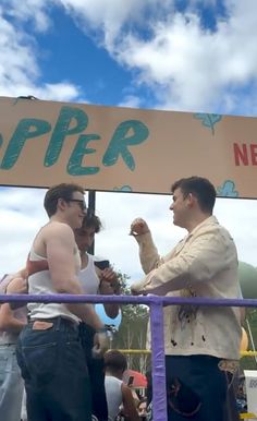 two men shaking hands under a sign at a festival