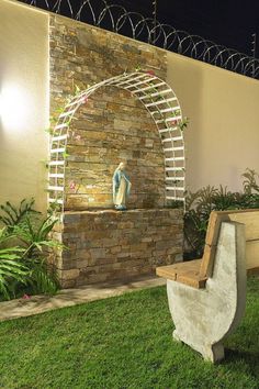 a bench sitting in front of a stone wall with a sculpture on it's side