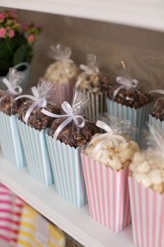 there are many cupcakes in the box on the shelf with ribbons around them