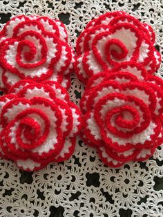 four red and white crocheted flowers on a doily