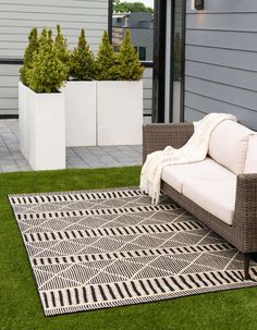 a white couch sitting on top of a grass covered field next to potted plants