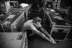 a man kneeling down in front of lots of suitcases with tattoos on his arm