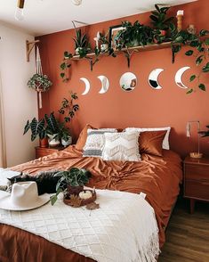 a bedroom with orange walls and plants on the wall above the bed, along with other decorations