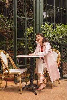 a woman is sitting at a table outside