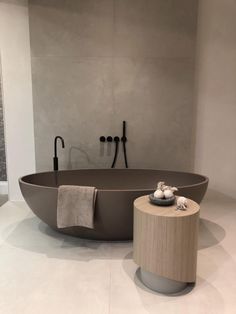 a large bath tub sitting in the middle of a bathroom next to a wooden stool