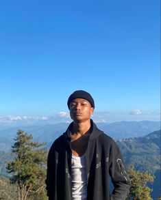 a young man standing on top of a mountain