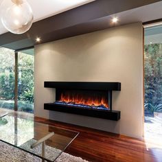 a modern fireplace in the middle of a living room with wood flooring and glass table