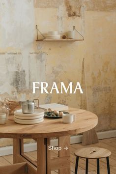 a wooden table with plates and cups on it in front of a wall that reads frama