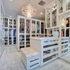 a walk in closet filled with lots of white furniture and glass doors on the walls