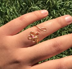 a woman's hand with a gold ring on top of it and grass in the background