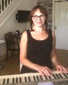 a woman wearing glasses sitting at a keyboard in front of a stair case and stairs