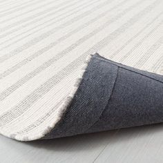 an area rug with white and grey stripes on the bottom half of it, laying on top of a wooden floor