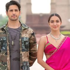 a man standing next to a woman in a pink sari on top of a field