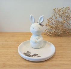 a white rabbit figurine sitting on top of a plate with a chain around it