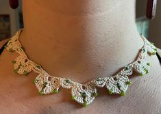 a woman wearing a white and green crochet necklace