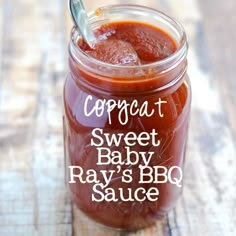 a glass jar filled with baby's bbq sauce on top of a wooden table