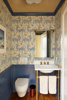 a bathroom with blue and gold wallpaper, white toilet and sink in it's corner