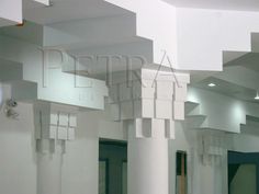 the interior of a building with white columns and lights on each side of the room