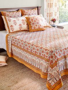 a bed with orange and white bedspread in a bedroom next to a window