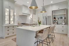 a large kitchen with white cabinets and an island that has four bar stools on it