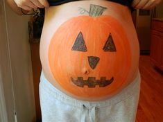 a pregnant woman with a pumpkin painted on her belly