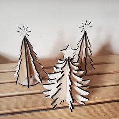 three paper christmas trees sitting on top of a wooden table