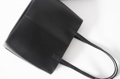 "This simple tote features black vegan (fake) leather, magnet top closure and internal pockets. Details: -Dimensions: 12\" length (top to bottom), 10\" bottom width, 7\" depth, 10\" X 7\" base (bottom) -Each shoulder strap measures approximately 23\" full length -Black vegan (fake) leather -Fabric interior lining (solid black) - color can be customized -Internal pockets: 1 slip pocket, 1 zippered pocket -Magnet top closure Because each bag is made by hand, the measurement is approximate and may Shopping Tote Shoulder Bag With Magnetic Closure, Daily Use Faux Leather Shoulder Bag With Magnetic Closure, Sleek Large Capacity Shoulder Bag For Shopping, Black Satchel With Magnetic Closure For Daily Use, Black Faux Leather Shoulder Bag For Work, Black Tote Satchel With Magnetic Closure, Black Bag With Magnetic Closure For Work, Black Shoulder Bag With Magnetic Closure, Everyday Black Shoulder Bag With Magnetic Closure