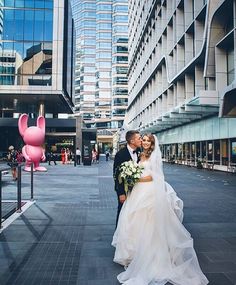 a bride and groom kissing in the middle of an empty street with tall buildings behind them