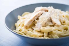 a blue bowl filled with pasta and meat