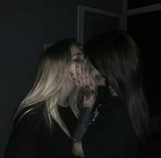 two women are kissing each other in the dark with their faces covered by tattoos on their hands