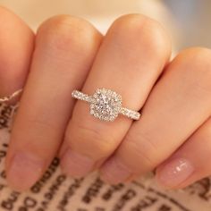 a woman's hand with a diamond ring on top of her finger and the other hand holding it