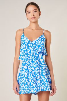 Keep your cool in this backlit floral motif romper. Asymmetrical ruffles top each other, sweeping across the chest and waist to add a voluminous flair. It's a fun fit to take on vacay or your next music festival. Go casual with some sneakers or dress it up with strappy lace up heels.- Zipper- Adjustable straps- Asymmetrical ruffle layers- Lined- Color: Blue IvorySize + Fit - Model is 5'8" and wearing size XS- Measurements taken from size S - Waist: 28 1/2" - Inseam: 2 1/2" Fabric Self: 100% Poly Floral Print Flirty Jumpsuits And Rompers For Spring, Flirty Floral Print Jumpsuits And Rompers For Spring, Flirty Jumpsuits And Rompers With Floral Print For Spring, Flirty Floral Print Jumpsuits For Spring, Blue Ruffled Jumpsuits And Rompers For Summer, Sleeveless Jumpsuits And Rompers With Ruffle Hem For Spring, Blue V-neck Jumpsuit With Ruffles, Blue Floral Print Jumpsuits And Rompers For Day Out, Spring Vacation Jumpsuits With Ruffle Hem