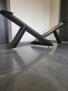 a metal sculpture sitting on top of a floor next to a wall in an empty room