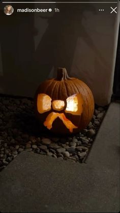 a carved pumpkin with a bow on it's head and eyes, sitting in front of a door