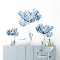 blue flowers on a white wall in a room with a gray chair and sideboard